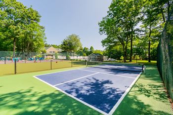 A Pickleball court surrounded by a fence and trees atat Mariner's Hill Apartments, Massachusetts.